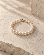 Pearl bracelet displayed on a softly lit neutral surface.